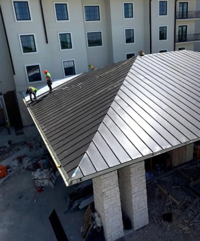 Crew installing standing seam metal roof panels on a commercial project in North Elba